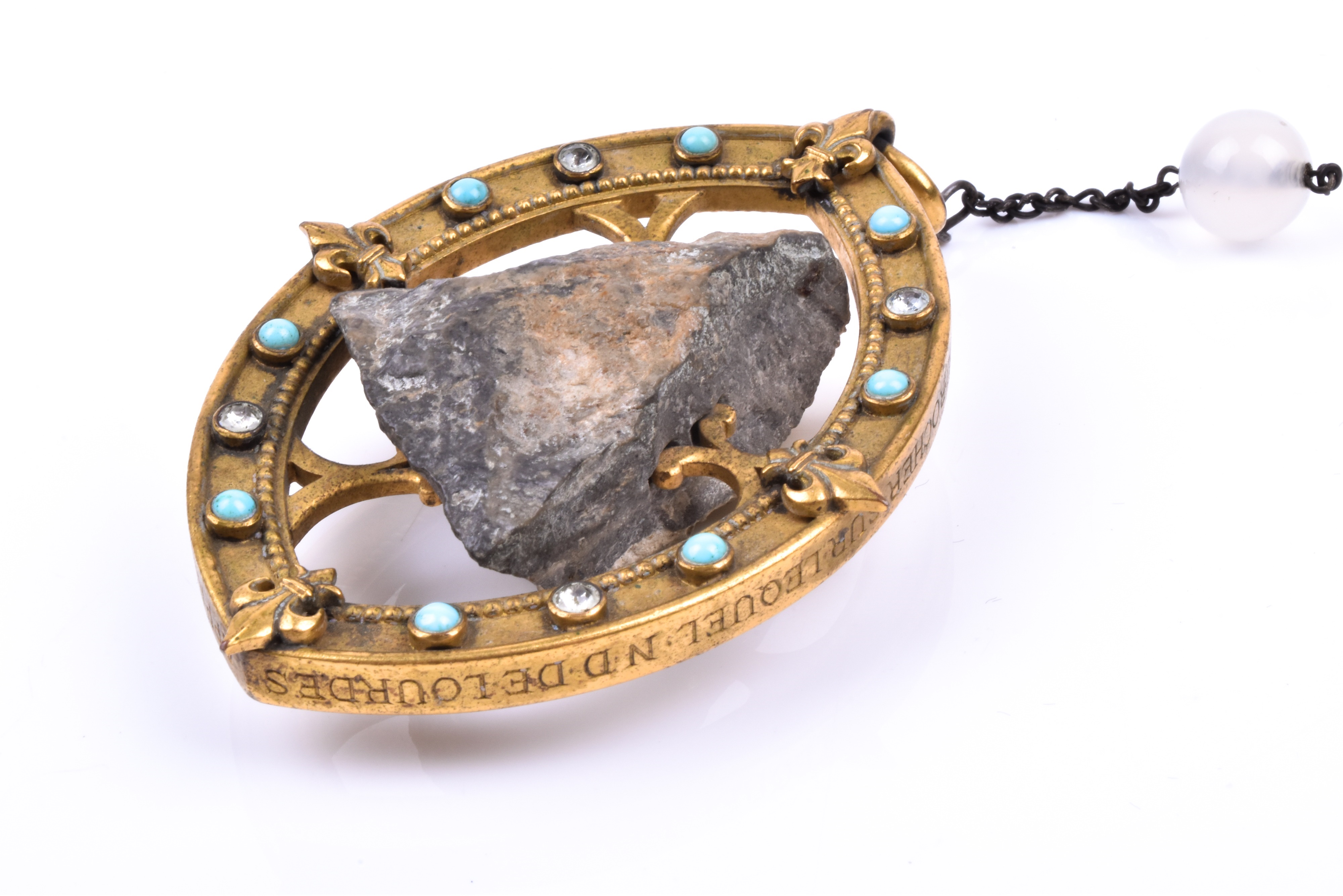 Lot: 781 : An unusual 19th century gilt metal pendant souvenir, enclosing a piece of rock from Lourdes on pale agate beaded rosary-style necklace/ Estimate £200-£300.